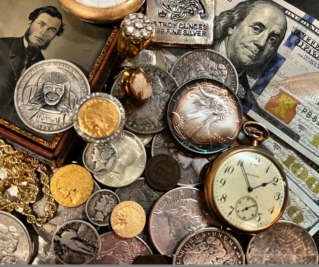 Silver and gold coins, a silver bar, paper currency and a pocket watch laid out at Warren Exchange for evaluation.